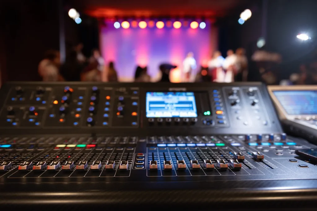 Audio engineer at a mixing console coordinating wireless microphone channels for a live event